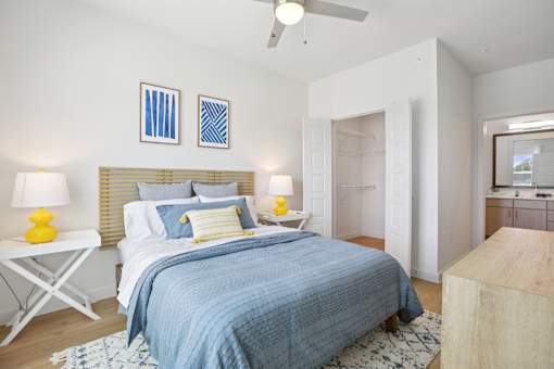 A bedroom with a bed, two lamps, and a ceiling fan. at Park South Apartments, Austin