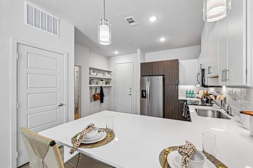 A modern kitchen with a dining table set for two.