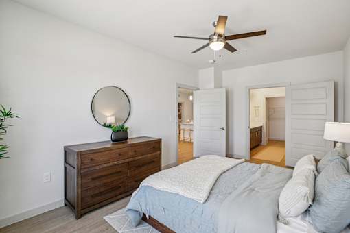 A bedroom with a bed, dresser, and mirror. at ThreeTwenty at the Vybe Apartments, Kyle, 78640