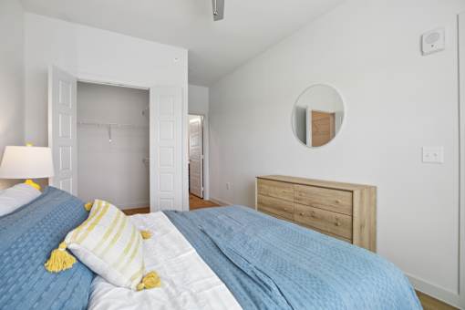 A bedroom with a bed, nightstand, and a mirror on the wall. at Park South Apartments, Austin, Texas