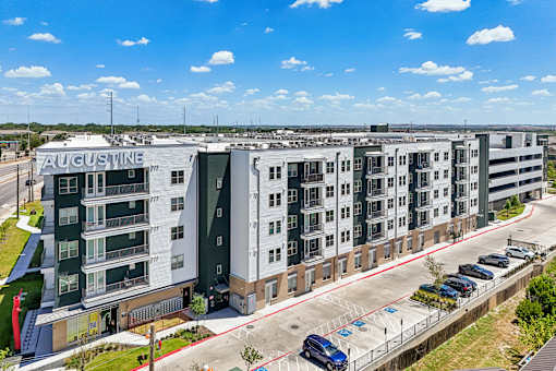 A large Augustine apartment complex with a parking lot in front.