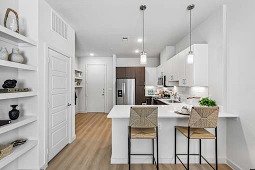 A kitchen with a white island and two chairs.