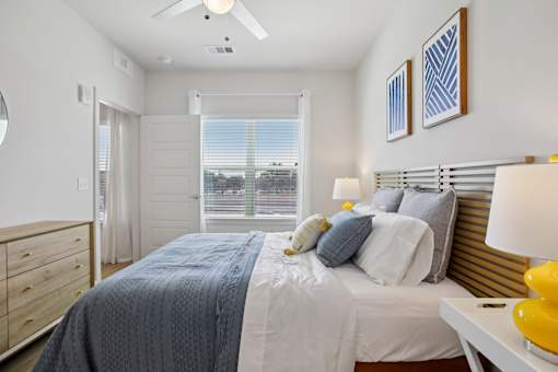 A bedroom with a bed, dresser, and ceiling fan. at Park South Apartments, Austin, TX, 78748