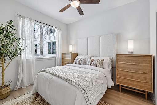 A bedroom with a white bed and a wooden dresser.