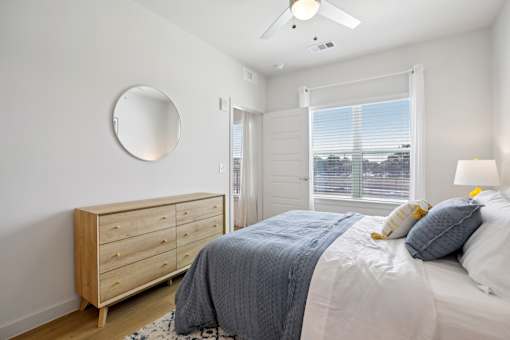 A bedroom with a bed, dresser, and window. at Park South Apartments, Austin, 78748