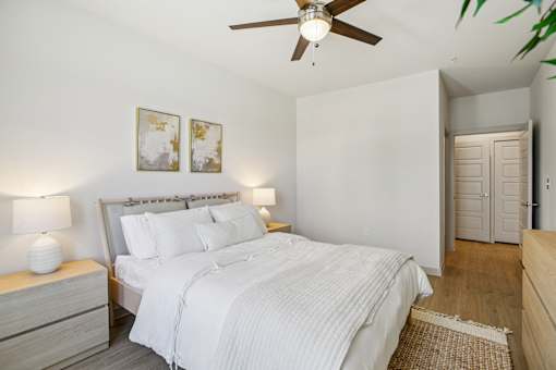 A bedroom with a bed, nightstand, and a ceiling fan. at ThreeTwenty at the Vybe Apartments, Kyle, Texas