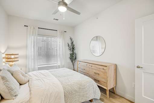 Bright bedroom with wood dresser and round mirror at Matador Apartments, Austin