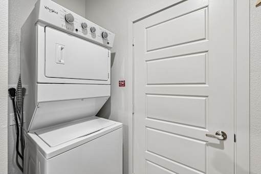A white Whirlpool oven and dryer in a small, white-walled laundry room.