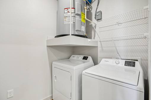 A wall-mounted washer and dryer are installed in a small room. at ThreeTwenty at the Vybe Apartments, Kyle