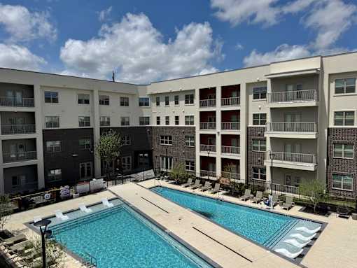 A large swimming pool in front of apartment buildings.