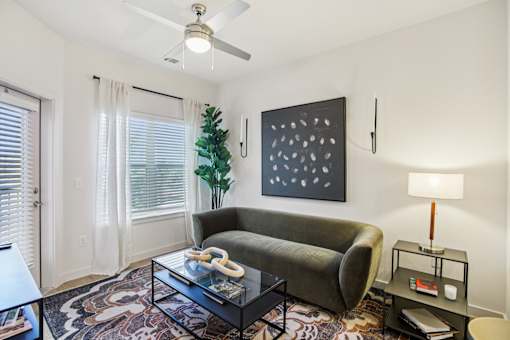 Living room with olive green sofa and artwork at Matador Apartments, Austin, TX