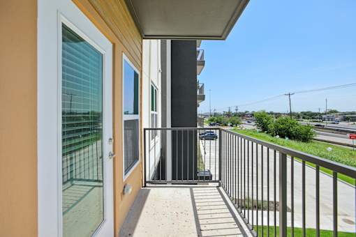 A balcony with a metal railing and a glass door leading to a patio. at Park South Apartments, Austin, TX, 78748