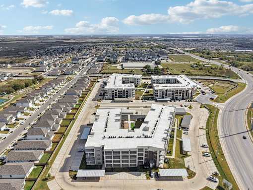 Aerial view of residential buildings and townhomes at Cantarra Apartments, Manor, TX 78653