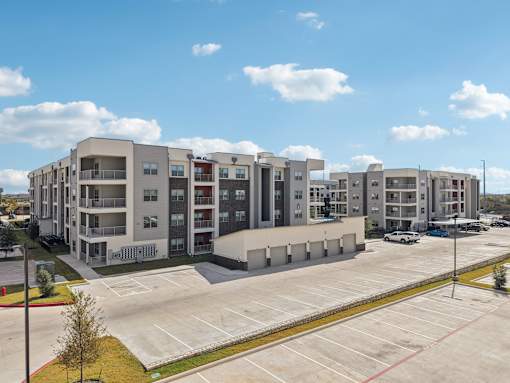 Modern apartment building with parking area at Cantarra Apartments, Manor, TX