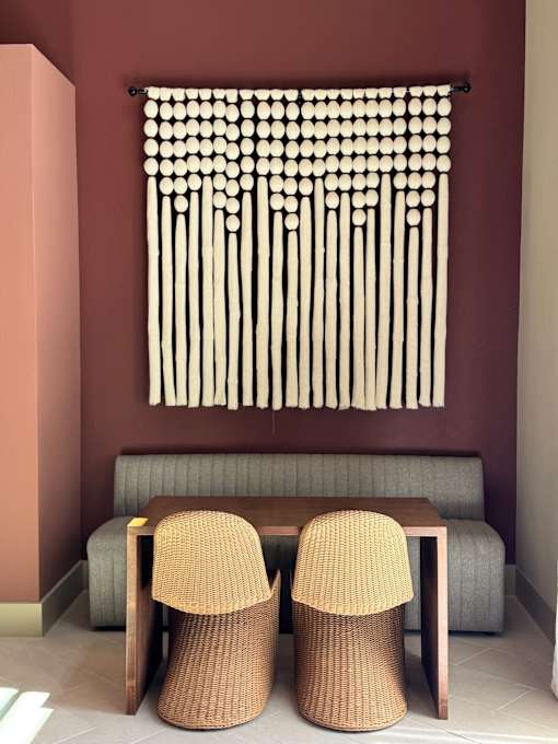 Two chairs sit in front of a window with a curtain made of white circles.