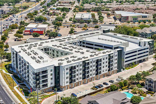 A large, modern building with a flat roof and a parking lot in front.