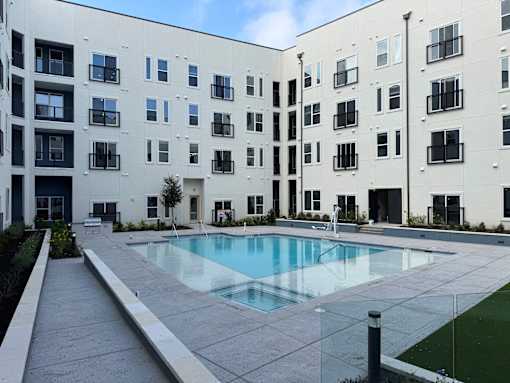 Resort-Style Pool area with building at ThreeTwenty at the Vybe Apartments, Kyle, 78640