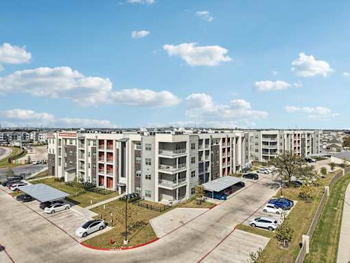 Modern apartment buildings with parking and sidewalks at Cantarra Apartments, Texas