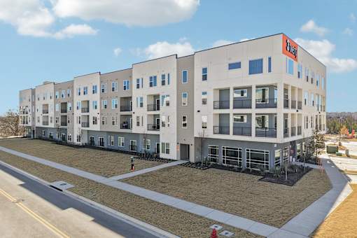 A large apartment complex with a red sign on the top floor. at ThreeTwenty at the Vybe Apartments, Texas, 78640