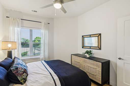 Bedroom with navy bedding and woven furniture at Matador Apartments, Austin