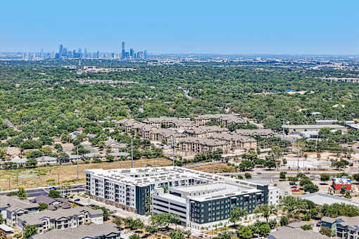 A large building complex is in the foreground with a city skyline in the background.