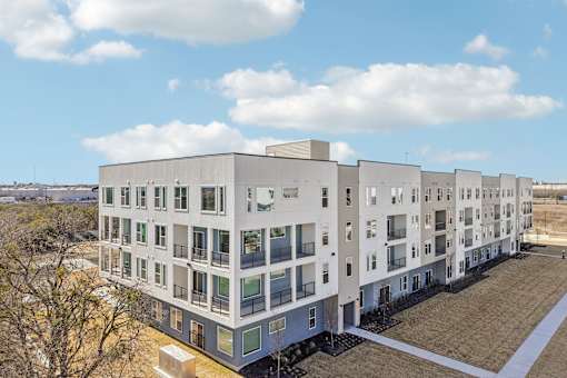 A large white building with many windows and balconies. at ThreeTwenty at the Vybe Apartments, Kyle, TX, 78640