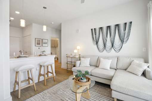A modern living room with a white couch and a bar area. at Park South Apartments, Austin, Texas