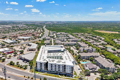 A large white building with a green roof is in the center of a busy intersection.