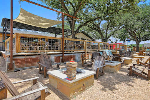 A wooden table is in the middle of a sandy area with chairs around it. at Park South Apartments, Austin, Texas