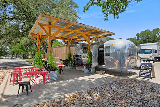 A wooden pergola is over a table with red chairs. at Park South Apartments, Austin, TX