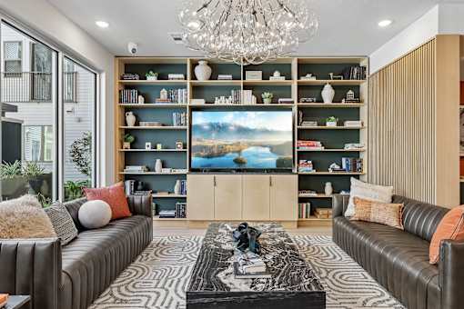 A living room with a large screen TV and a chandelier.