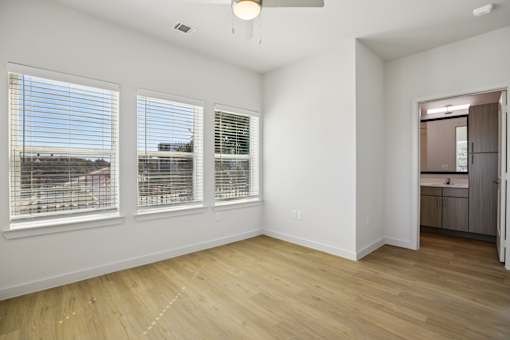 Empty bedroom with three windows and hardwood floors 1 at Matador Apartments, Austin, Texas