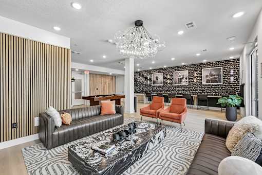 A living room with a black and white patterned rug, a black coffee table, and a chandelier.