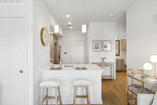 A white kitchen with a bar and stools. at Park South Apartments, Texas, 78748