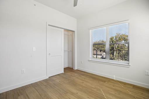 Empty bedroom with hardwood flooring and window at Matador Apartments, Texas