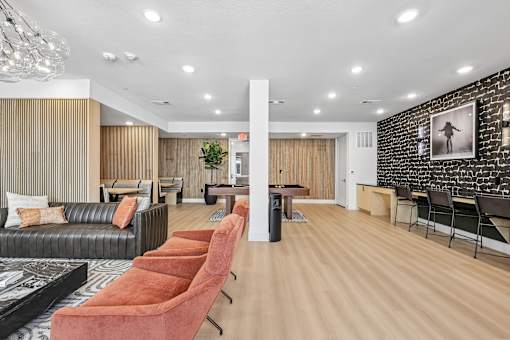 A living room with a black couch, a coffee table, and a row of orange chairs.