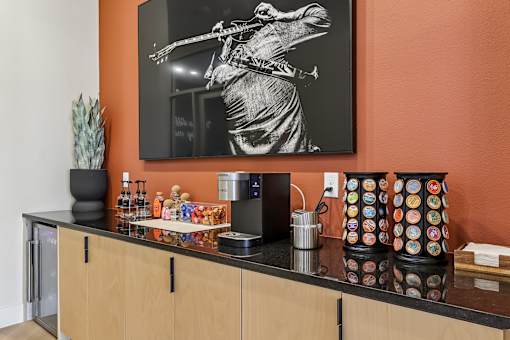 A kitchen with orange walls has a black and white photo of a man playing a guitar hanging on the wall.