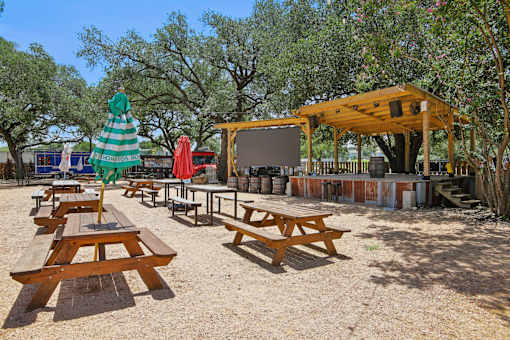 Picnic tables and a screened pavilion are set up in a park. at Park South Apartments, Austin, TX