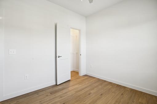 Empty bedroom with open door and wood flooring 1 at Matador Apartments, Texas