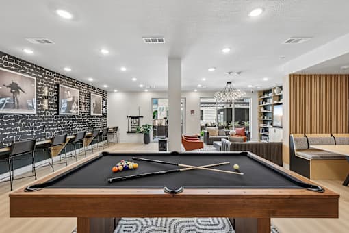 A pool table is in the middle of a room with a black and white striped rug.