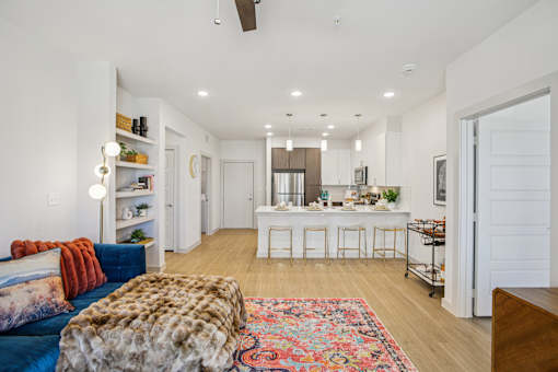 A living room with a blue couch and a furry ottoman. at ThreeTwenty at the Vybe Apartments, Texas