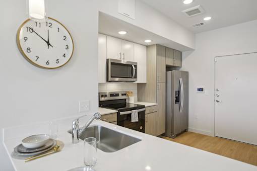 A modern kitchen with a clock on the wall. at Park South Apartments, Austin, TX