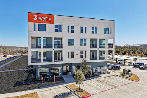 A modern building with the sign at ThreeTwenty at the Vybe Apartments, Kyle