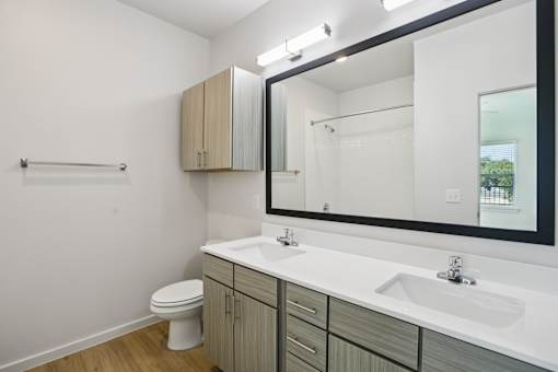 Double sink bathroom with wood grain vanity at Matador Apartments, Austin