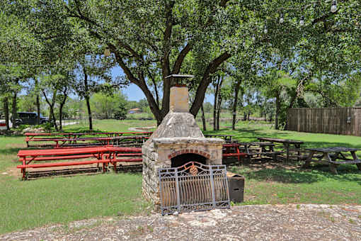 A stone fireplace is in the middle of a picnic area. at Park South Apartments, Texas, 78748