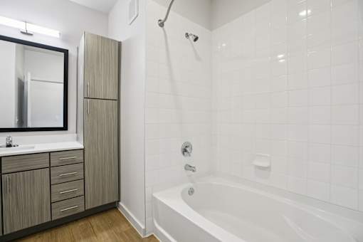 Bathroom with white tiled tub and tall cabinet at Matador Apartments, Texas