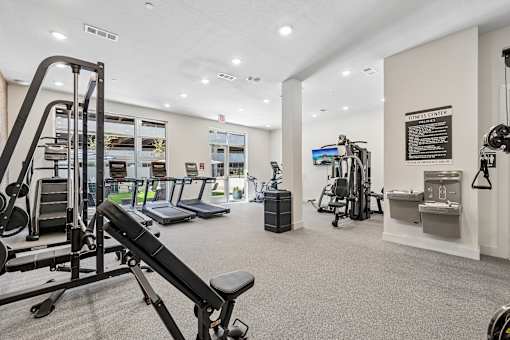 A gym with a variety of equipment including a squat rack, bench press, and a rowing machine.