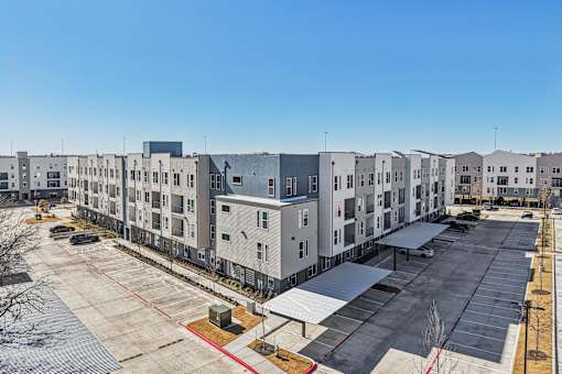 A parking lot in front of apartment buildings. at ThreeTwenty at the Vybe Apartments, Kyle, TX, 78640
