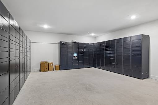 A room with a wall of lockers and a couple of cardboard boxes on the floor.