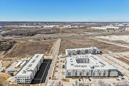 An aerial view of a large industrial complex with two main buildings and a parking lot. at ThreeTwenty at the Vybe Apartments, Kyle